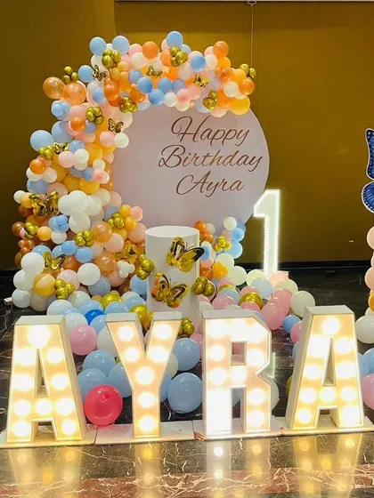 A beautiful butterfly theme for Ayra's first birthday. We used pastel orange, blue, and pink balloons, butterfly accents, and large marquee letters to spell out her name.