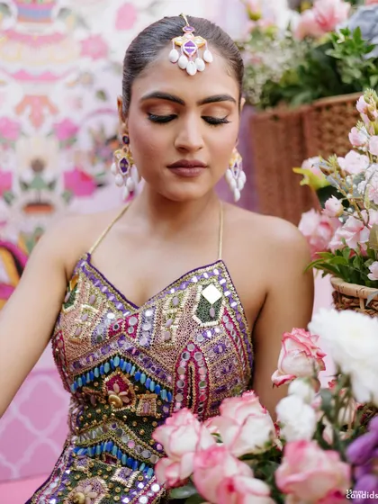 A close-up of the bride's sleek Mehendi look, with a simple, tight braid that allows her colorful outfit and jewelry to take center stage.