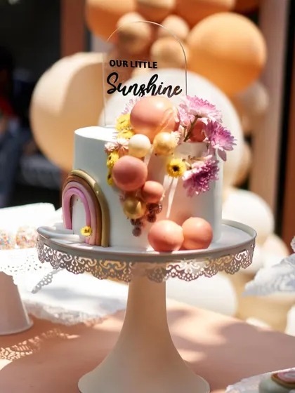 Our Little Sunshine." This beautiful cake with a rainbow and floral details was the centerpiece of a modern boho-themed birthday party.