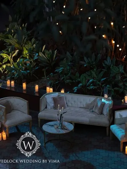 The outdoor lounge area for a reception, illuminated by fairy lights and candles. The elegant white furniture and surrounding greenery created a cozy and romantic space for guests to relax.