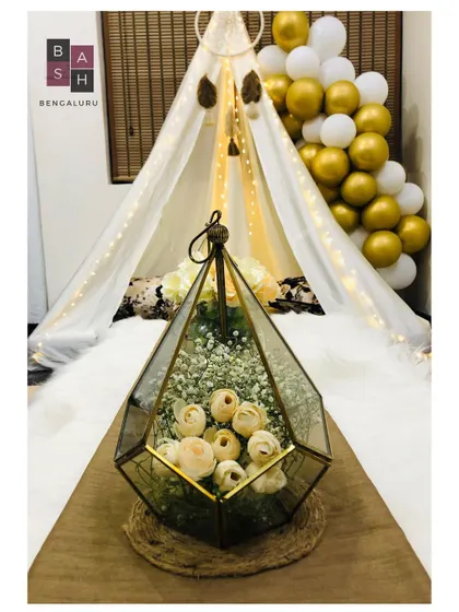 It's all in the details. This close-up shows one of our elegant geometric terrariums filled with delicate flowers, a key element in our chic canopy setups that adds a touch of sophisticated charm to your romantic evening.