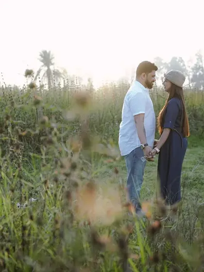 A quiet, face-to-face moment in a field, capturing the intimacy and anticipation before the wedding.