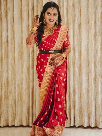 A full view of this elegant red saree and custom blouse combination. The outfit is paired with a sleek black belt, adding a modern touch to the traditional look.