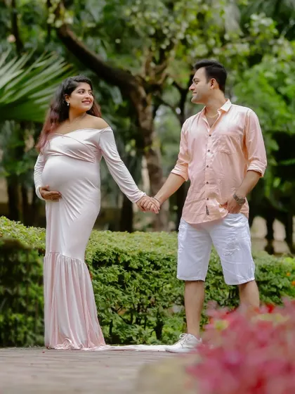 A candid shot of the couple holding hands and sharing a look of love and anticipation during their park maternity session.