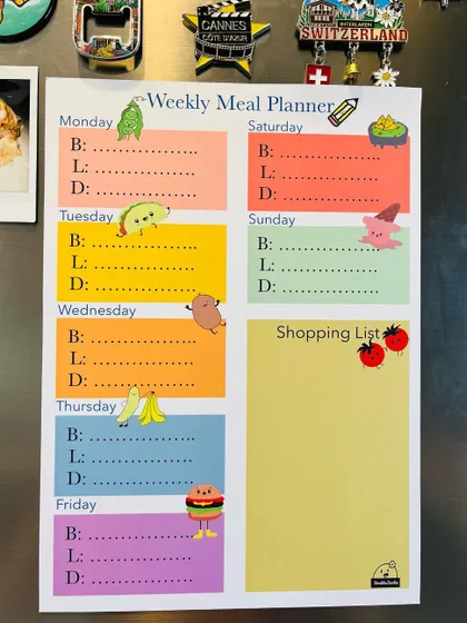 The full view of my reusable weekly meal planner, featuring cute food doodles and separate sections for each day plus a shopping list.
