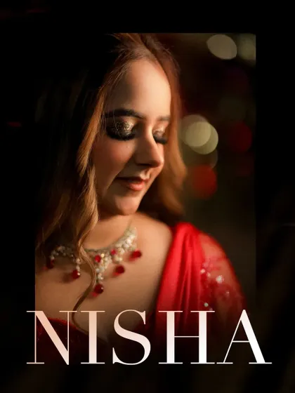 A close-up, softly lit portrait of Nisha, capturing her beautiful makeup and the sparkle of her necklace.