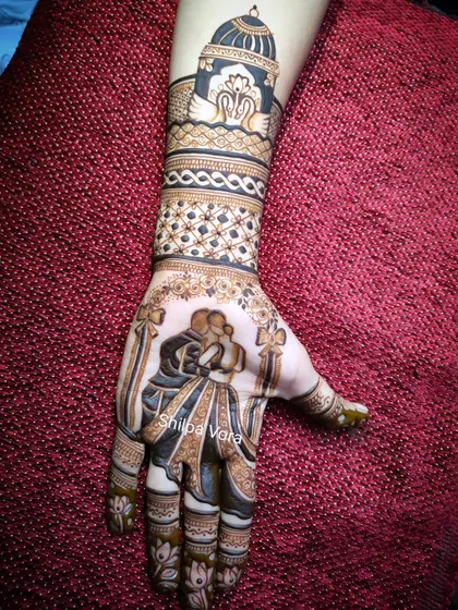An engagement mehndi design featuring a romantic couple silhouette. The design extends up the arm with swan motifs and intricate bands.