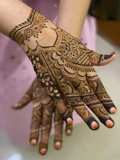 A close-up view of a detailed design on the back of the hand, showing how different elements like scallops, leaves, and swirls come together.