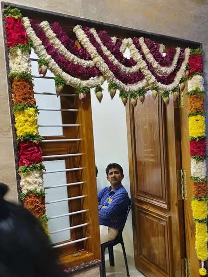 A door decorated with garlands of jasmine and other flowers in a tri-color design. The hanging lotus buds add a special touch.