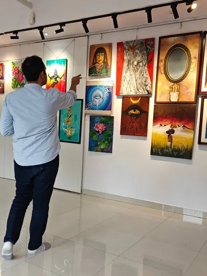 A visitor points out a detail in an artwork during our "Vernissage" Art Exhibition. We encourage our guests to look closely and connect with the diverse works on display.