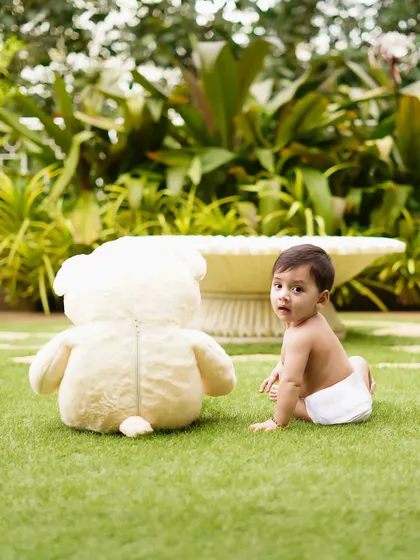 The baby turns to look at the camera, a moment of connection during his outdoor playtime. Natural light and settings create beautiful, authentic portraits.