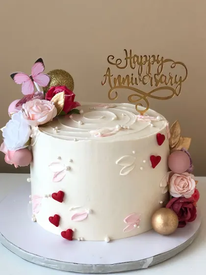 A simple and sweet anniversary cake with hearts, flowers, and a touch of gold.