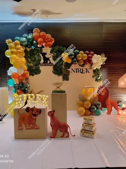 A "Hakuna Matata" Lion King theme for a first birthday party. This jungle-inspired decoration includes character cutouts of Simba and Nala, marquee letters and numbers, and a balloon arrangement in earthy tones to bring the safari to your event.