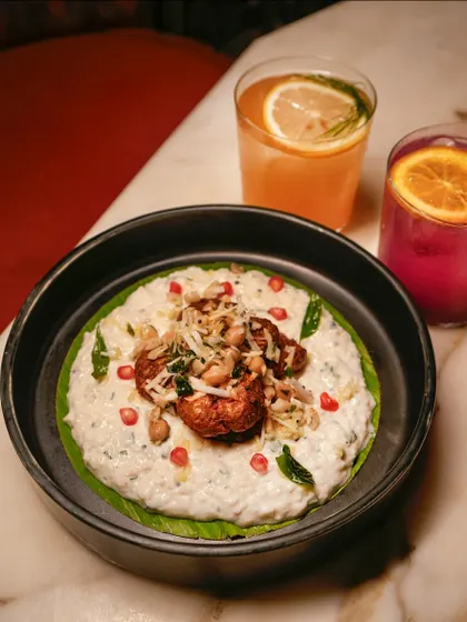 A bowl of our creamy curd rice, topped with fried chicken and pomegranate seeds. It's a cooling and textural dish that balances spice perfectly.