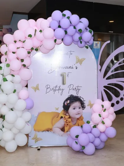 A welcome photo board for a butterfly-themed first birthday. The pastel balloon garland and large butterfly wing cutout create a beautiful photo opportunity.