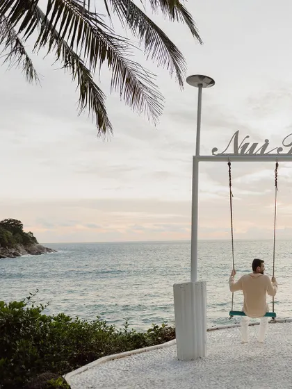 A solitary, contemplative portrait of the groom-to-be on a swing overlooking the ocean at Nui Beach, setting a peaceful and romantic tone.