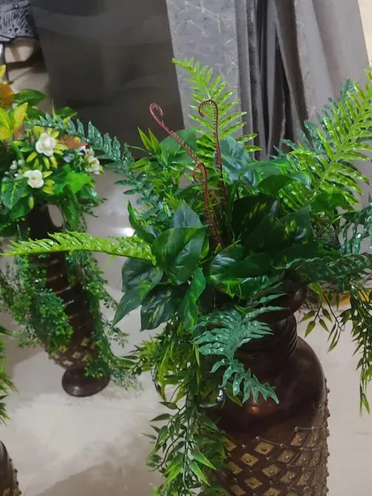 A close-up of one of the artificial fern arrangements in a decorative vase. The different leaf shapes and textures make the arrangement look very natural.