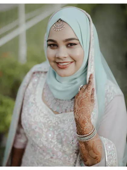 A close-up of the bride, her hand with intricate henna gently touching her face, showcasing her beautiful smile.