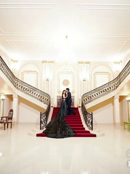 A breathtaking wide-angle shot of a couple on a grand double staircase, emphasizing the scale and opulence of the location for a truly cinematic feel.