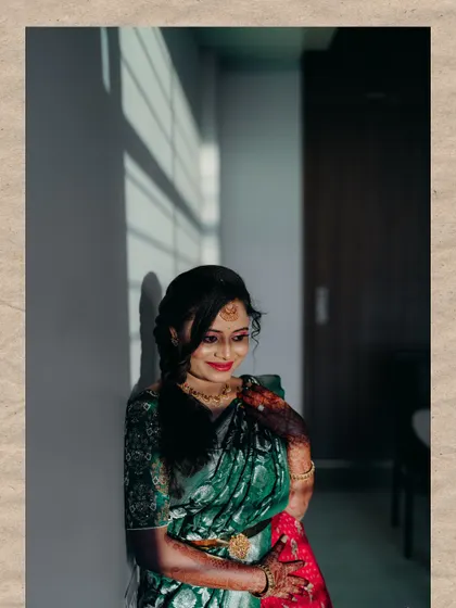 A portrait of a bride in a green and red half-saree, captured with beautiful natural light and shadows.