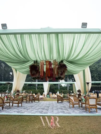A wide view of one of the main tented structures. The soft green and cream draping creates a light and airy feel, perfect for a daytime celebration.