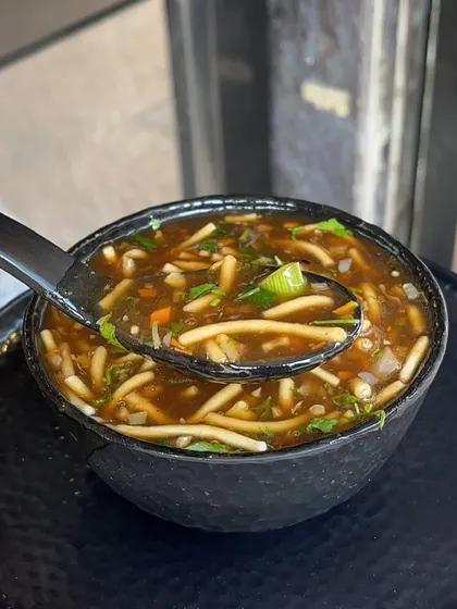 A spoonful of my hearty Manchow soup, filled with finely chopped vegetables and noodles.