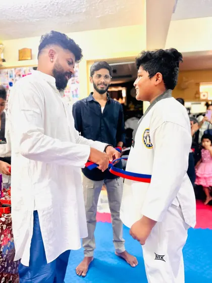 A student smiles as he receives his red and blue belt.