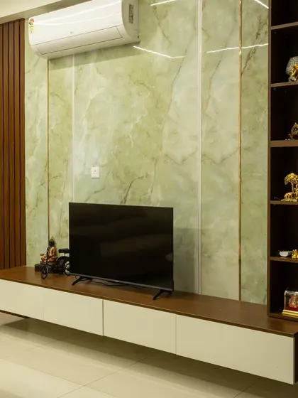 This living room features a stunning TV unit with a green marble-finish back panel and a floating wooden console, combining natural textures with modern design.