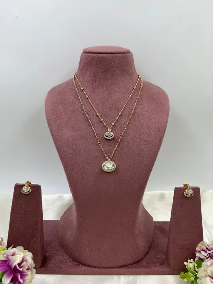 The Kritika Dual Shine Necklace Set. This delicate piece features two layered chains with unique, color-shifting stones, available in purple, green, and white.
