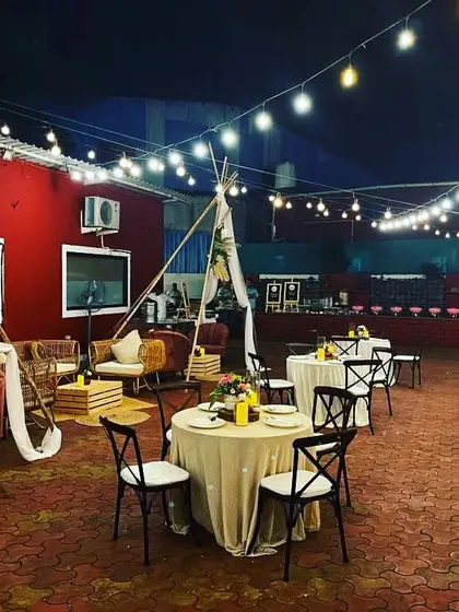 A full view of a boho-chic outdoor lounge setup. We combined different seating styles, including teepees and rattan chairs, with warm string lighting to create a relaxed and stylish vibe.