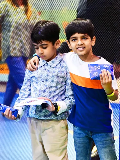 Two boys show off their Raksha Bandhan gifts and crafts, capturing a moment of sibling joy.
