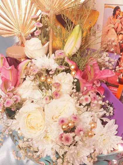 A luxurious floral gift hamper, perfect for an anniversary. This arrangement combines fresh flowers with gourmet chocolates and a personalized photo frame, creating a truly romantic and impressive gift.