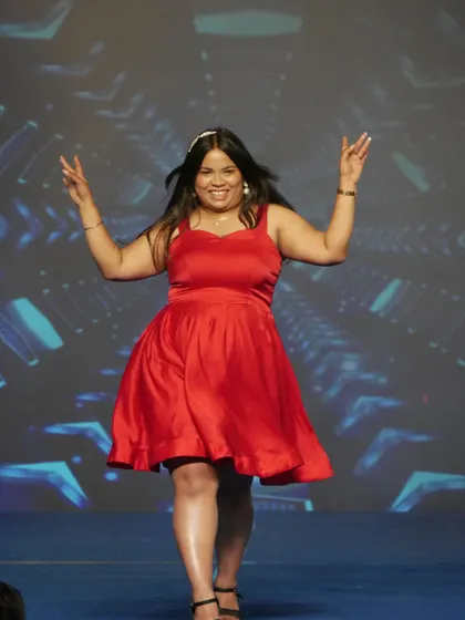 A student in a vibrant red dress walks the ramp during the cultural segment of our annual show.