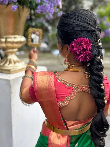 The bride admiring her final look. The combination of a perfectly draped saree, traditional jewelry, and a beautiful hairstyle creates a timeless and elegant appearance.