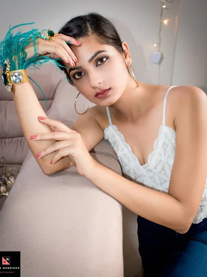 A fashion-forward portrait featuring bold accessories like a turquoise feather bracelet. The model's direct gaze and the stylish props create a modern and engaging image.