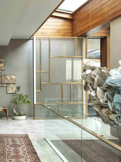 This view showcases the origami installation in context with the home's interior architecture. The organic, flowing shapes of the artwork provide a soft counterpoint to the clean lines of the glass balustrade and wood-paneled ceiling.