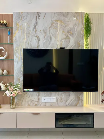 This TV unit is a masterclass in modern design, featuring a marble-patterned backdrop with gold veining, vertical fluted panels, and integrated lighting that creates a warm, ambient glow.