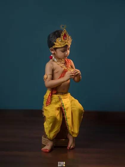 A thoughtful little Krishna, dressed in yellow silk dhoti and a crown.