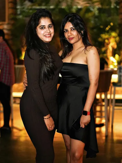 Two friends in black dresses, smiling for a photo.