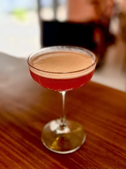 A beautifully crafted cocktail with a rich, frothy top, served in a classic coupe glass. The presentation is just as important as the taste, ensuring a sophisticated drinking experience.