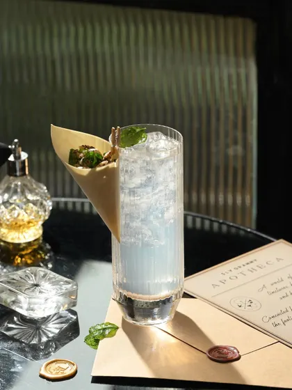 The Castaway Collins, presented in a tall, fluted glass with its signature paper cone holding crispy fried herbs.
