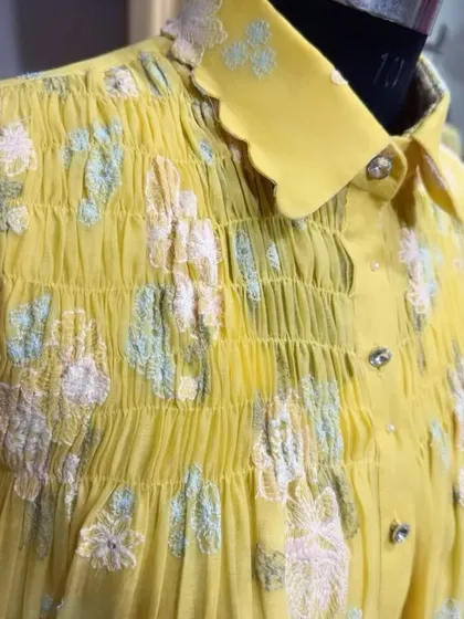 A close-up shot of the Chanderi floral embroidered shirt. This view highlights the detailed smocking and the texture of the floral threadwork, showcasing the quality of the craftsmanship.