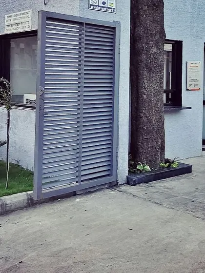 An exterior detail showing a louvered service gate and how the building form accommodates an existing tree, demonstrating thoughtful integration with the site.