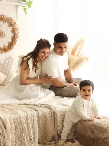 A candid moment of exploration. As the little one crawls to the edge of the bed, his parents watch with loving smiles, perfectly capturing a day in the life of a young family.