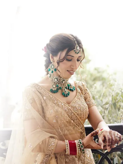 A classic, softly lit portrait of the bride looking down, highlighting her intricate jewelry and elegant hairstyle for her mountain wedding.