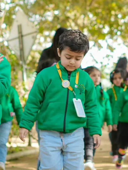 A line of students in green jackets walking along a path at the farm, ready for their day of exploration.