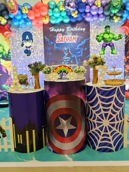 A close-up of the themed pedestals at Satyam's superhero party, featuring Captain America's shield and a cityscape design.