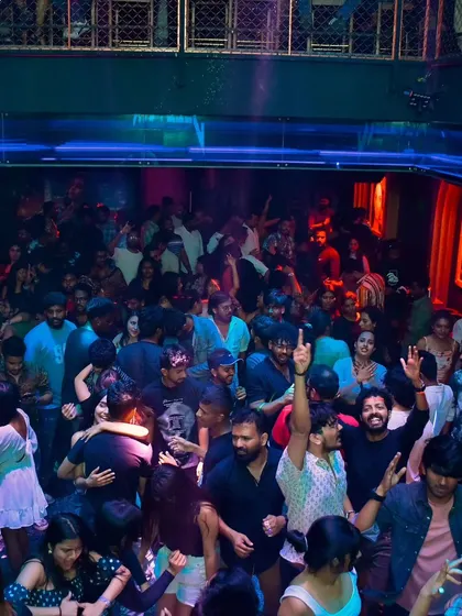 This is the energy I live for. A wide shot of a multi-level club in Bangalore with every space filled with people dancing to the beats I'm dropping.