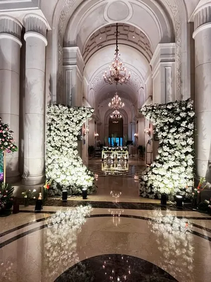 A grand entrance corridor at The Leela Palace. We created a majestic walkway with towering floral structures made of white roses, leading into the main event hall.