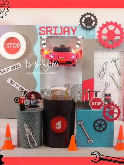A close-up of the main stage for the mechanic-themed party, featuring a red car, tool-themed decor, and a personalized name sign.